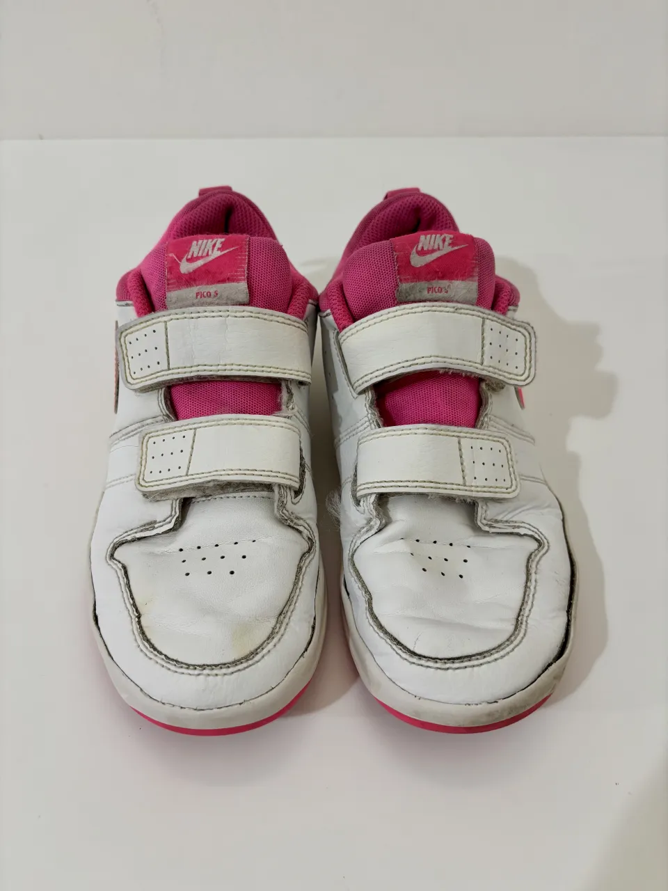 Zapatillas deportivas blancas y rosas con abrojo, marca Nike.