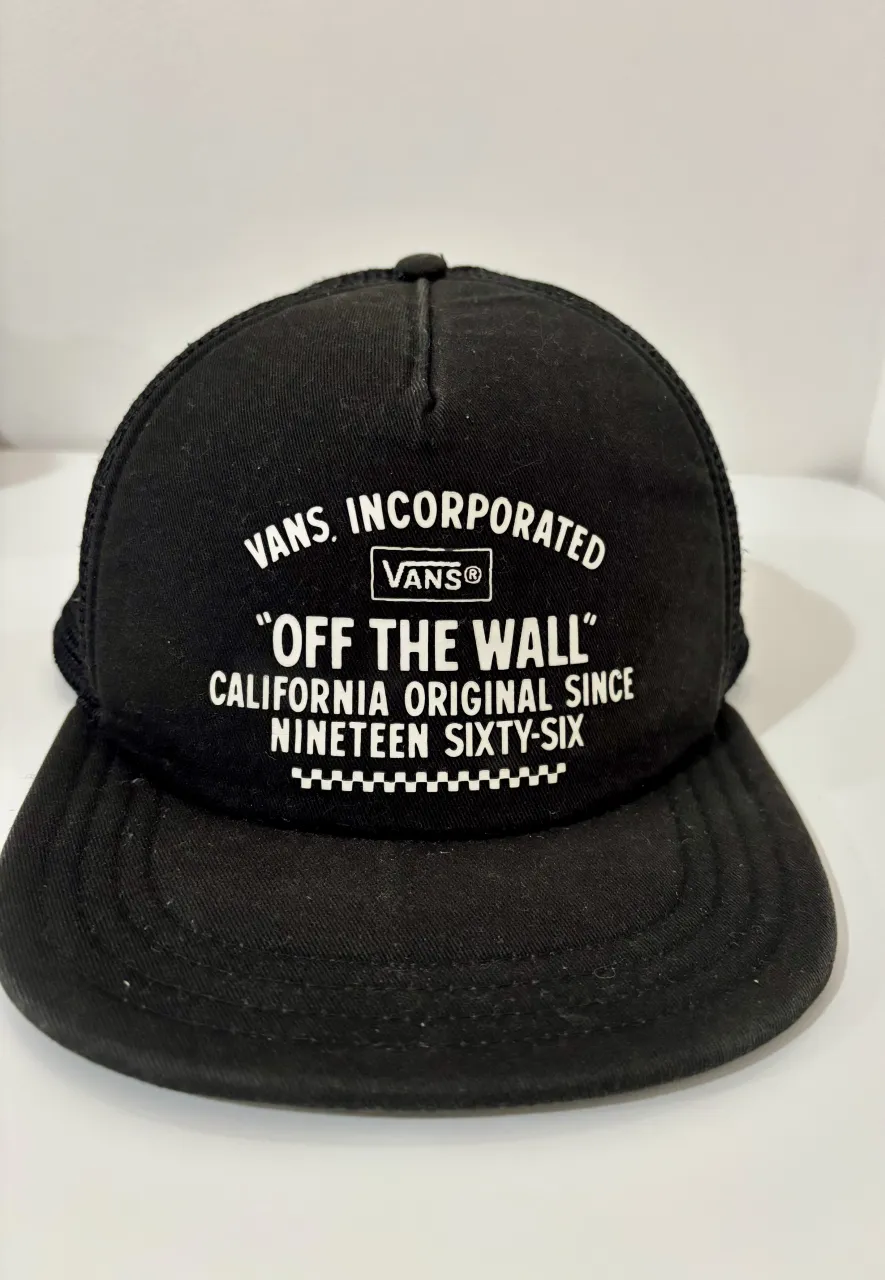Gorra trucker negra de Vans, con el logo "Off The Wall" bordado en blanco. Ideal para un look casual y urbano.