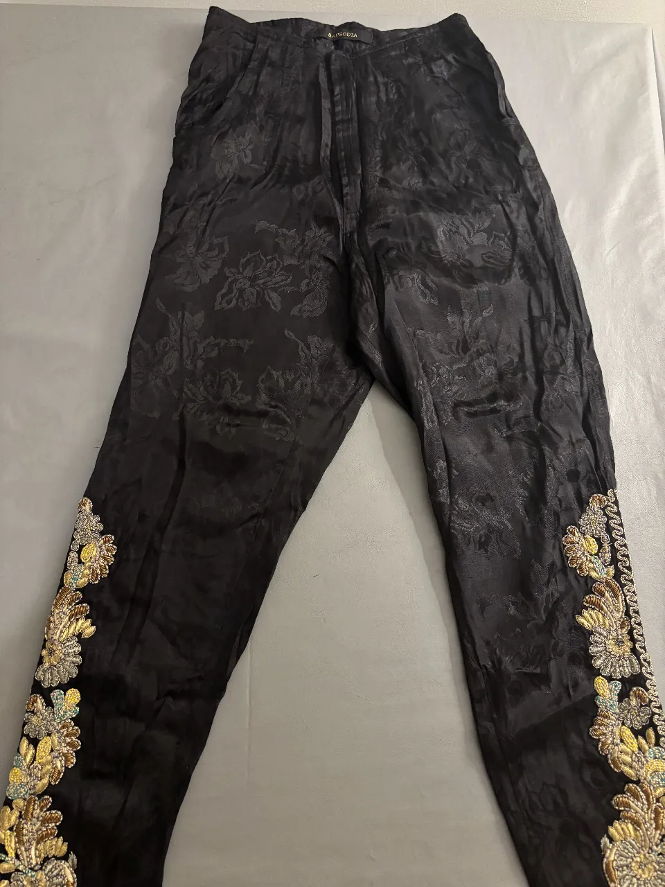Pantalón sastrero negro con bordados dorados en los laterales inferiores. Ideal para eventos formales o fiestas.