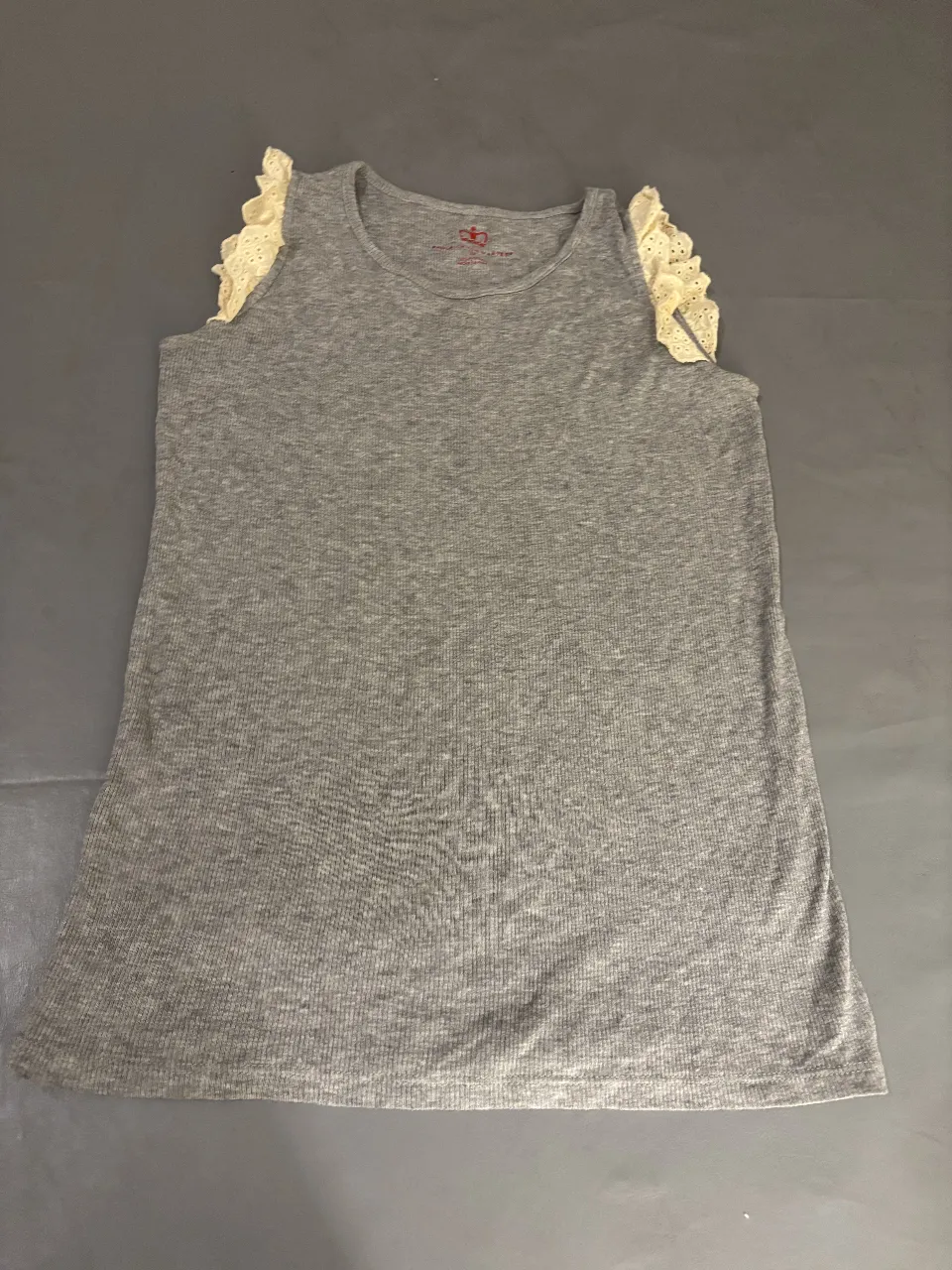 Musculosa gris con detalles de volados en los hombros. Ideal para un look casual y fresco.