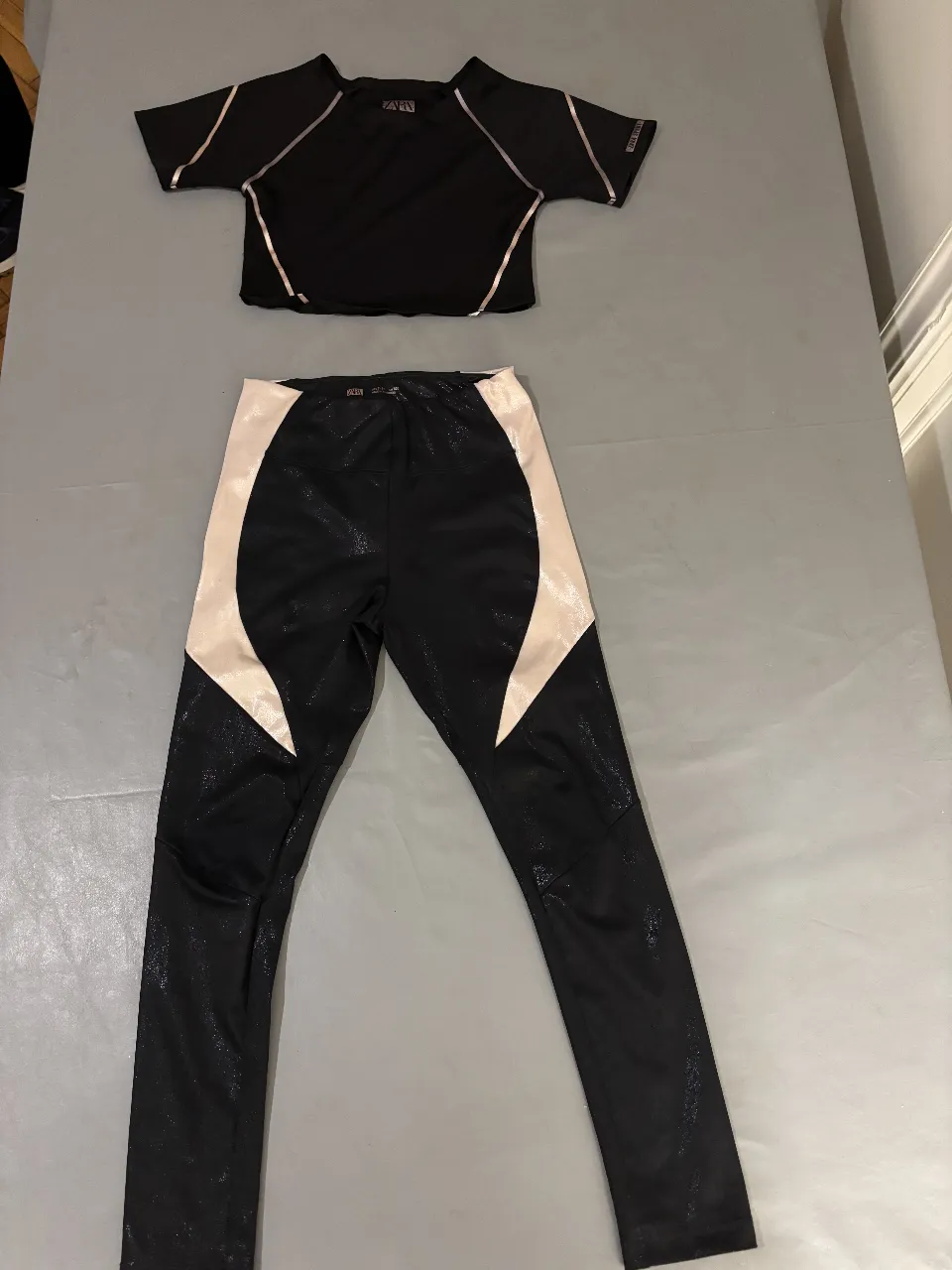 Conjunto deportivo de niña, top manga corta con detalles en rosa y calzas con paneles en rosa y negro. Ideal para entrenamientos.