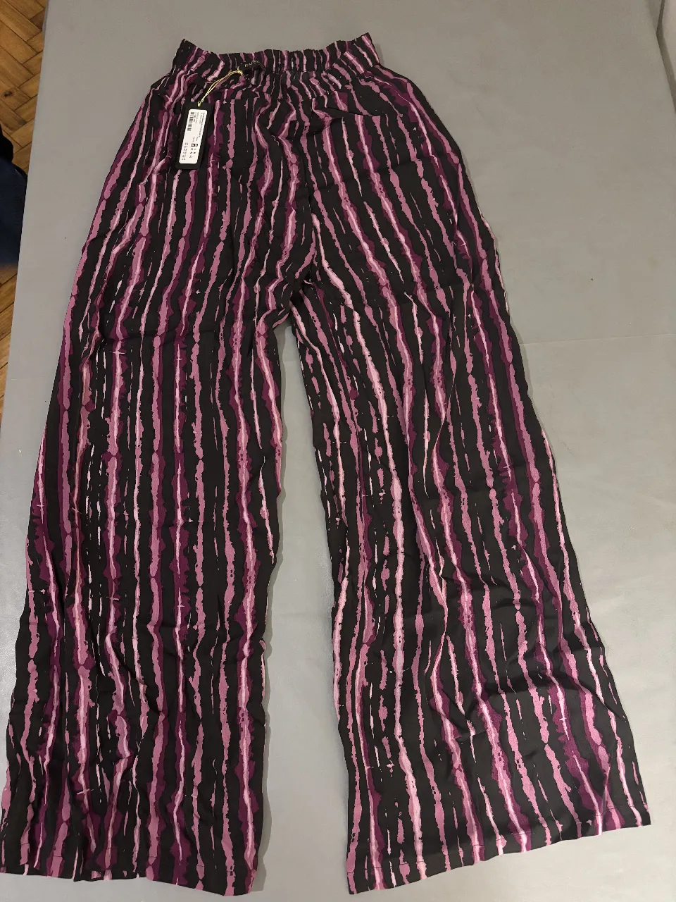 Pantalón suelto de mujer con estampado de rayas verticales en tonos negro y rosa. Ideal para un look casual y cómodo.