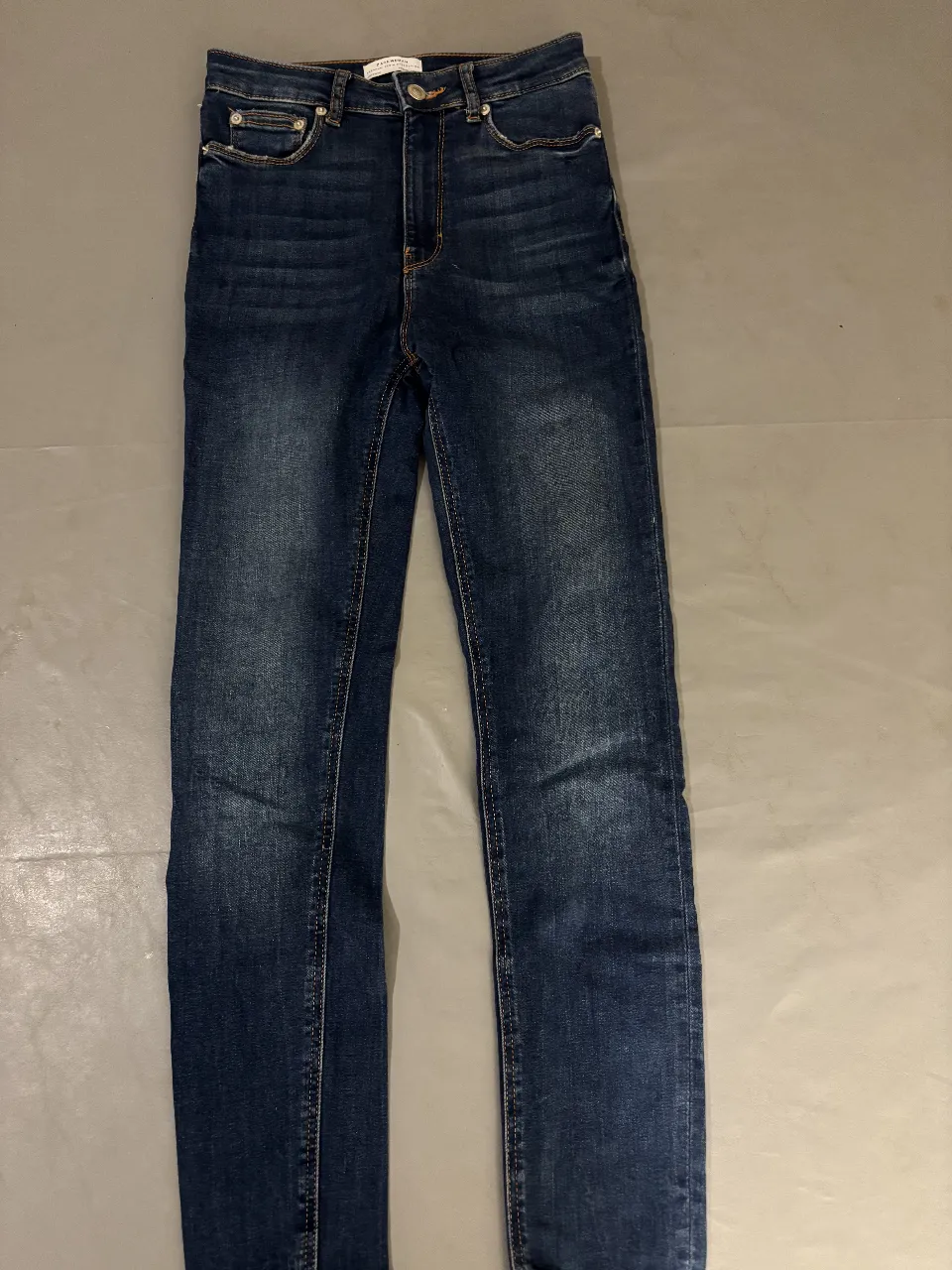 Jeans de mujer tiro alto, corte recto, color azul oscuro con efecto gastado. Ideal para un look casual y moderno.