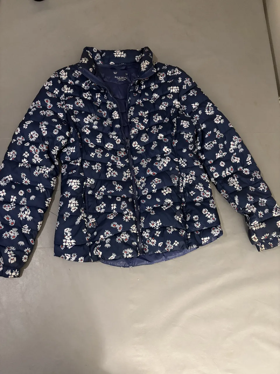 Campera de pluma para mujer, azul marino con estampado floral blanco. Ideal para el invierno, con cierre y cuello alto. 