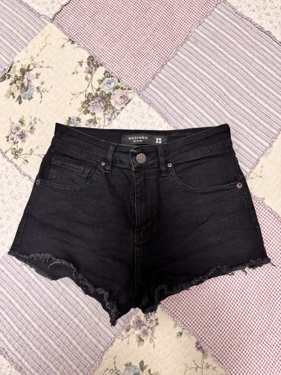 short de jean negro tiro alto KOSIUKO usado con detalles deshilachados. tiene bolsillos delanteros y traseros.