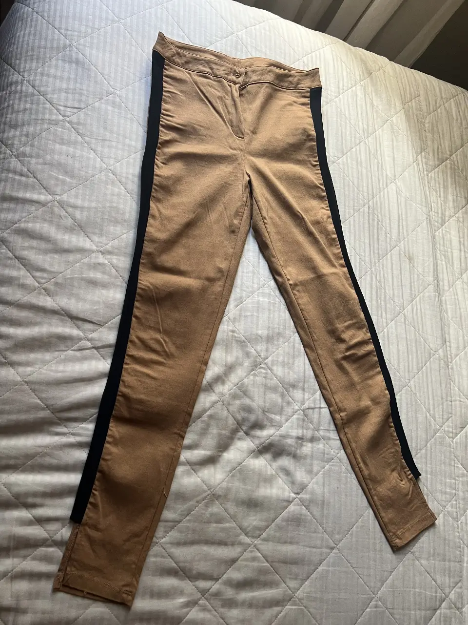 Pantalón sastrero de mujer en color marrón con detalles en negro en los laterales. Ideal para un look elegante y moderno. Tiro alto. Detalle de abertura en el tobillo. Chupin. Elastizado. Sería para talle 38/40.