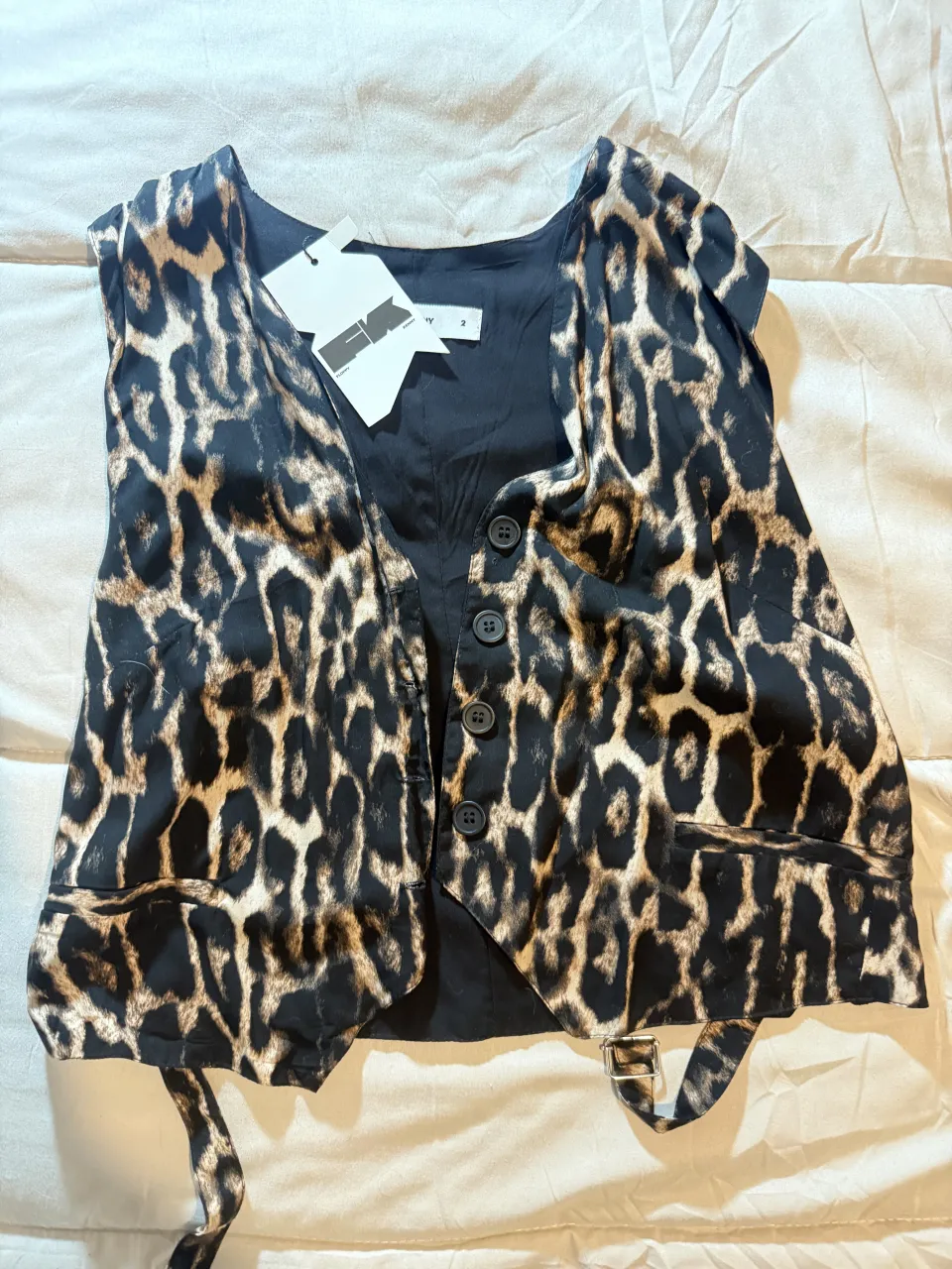 Chaleco sastrero estampado de leopardo con botones negros y tiras ajustables en la parte inferior.