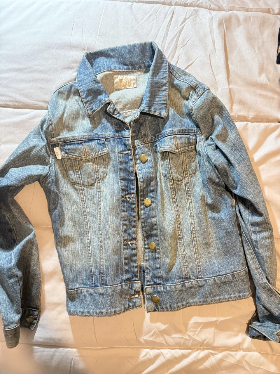 Campera de jean clásica vintage, color azul claro, con botones dorados y bolsillos frontales.