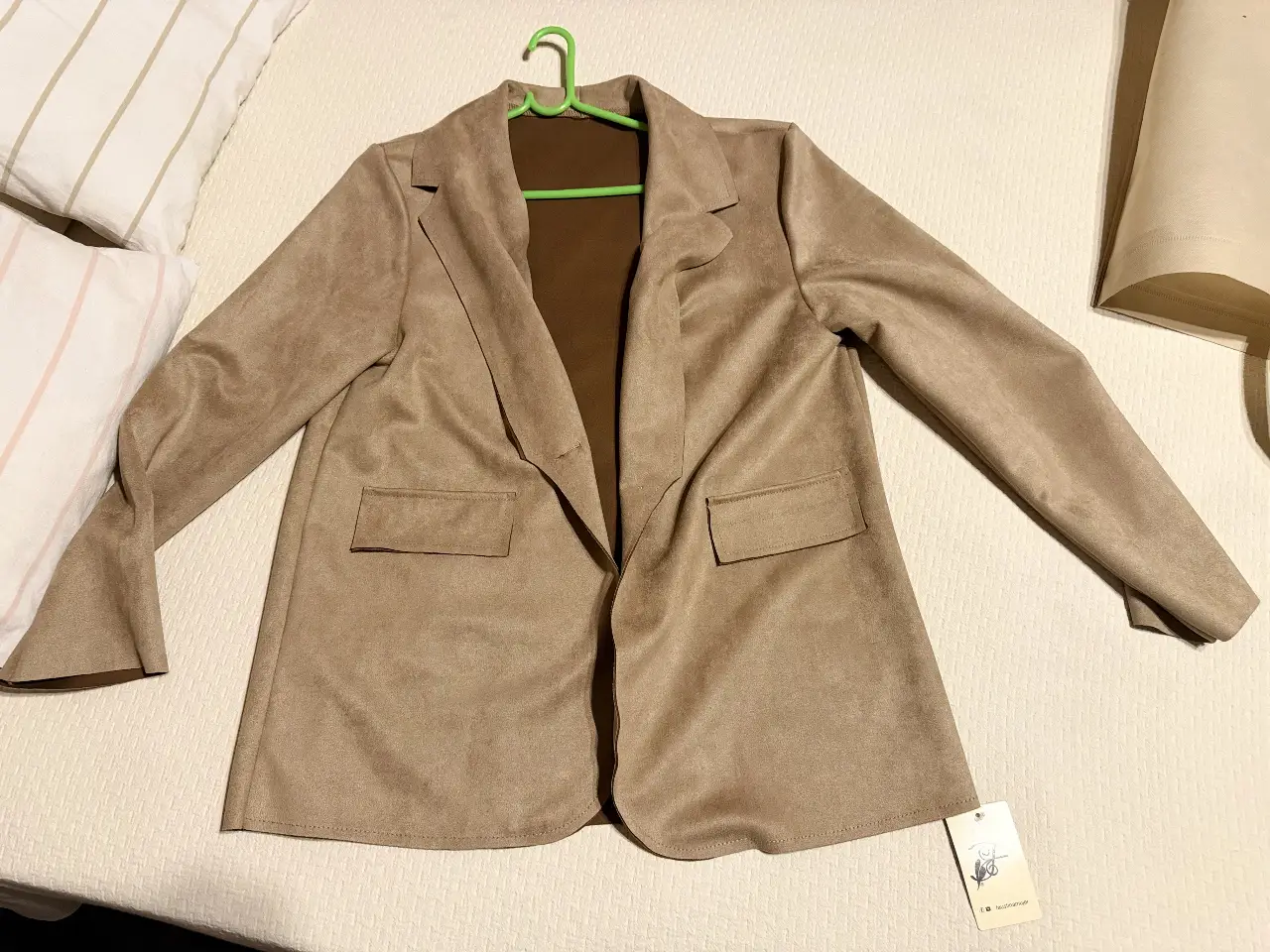 Blazer de gamuza color marrón claro, con solapas y bolsillos delanteros. Ideal para un look elegante y versátil.