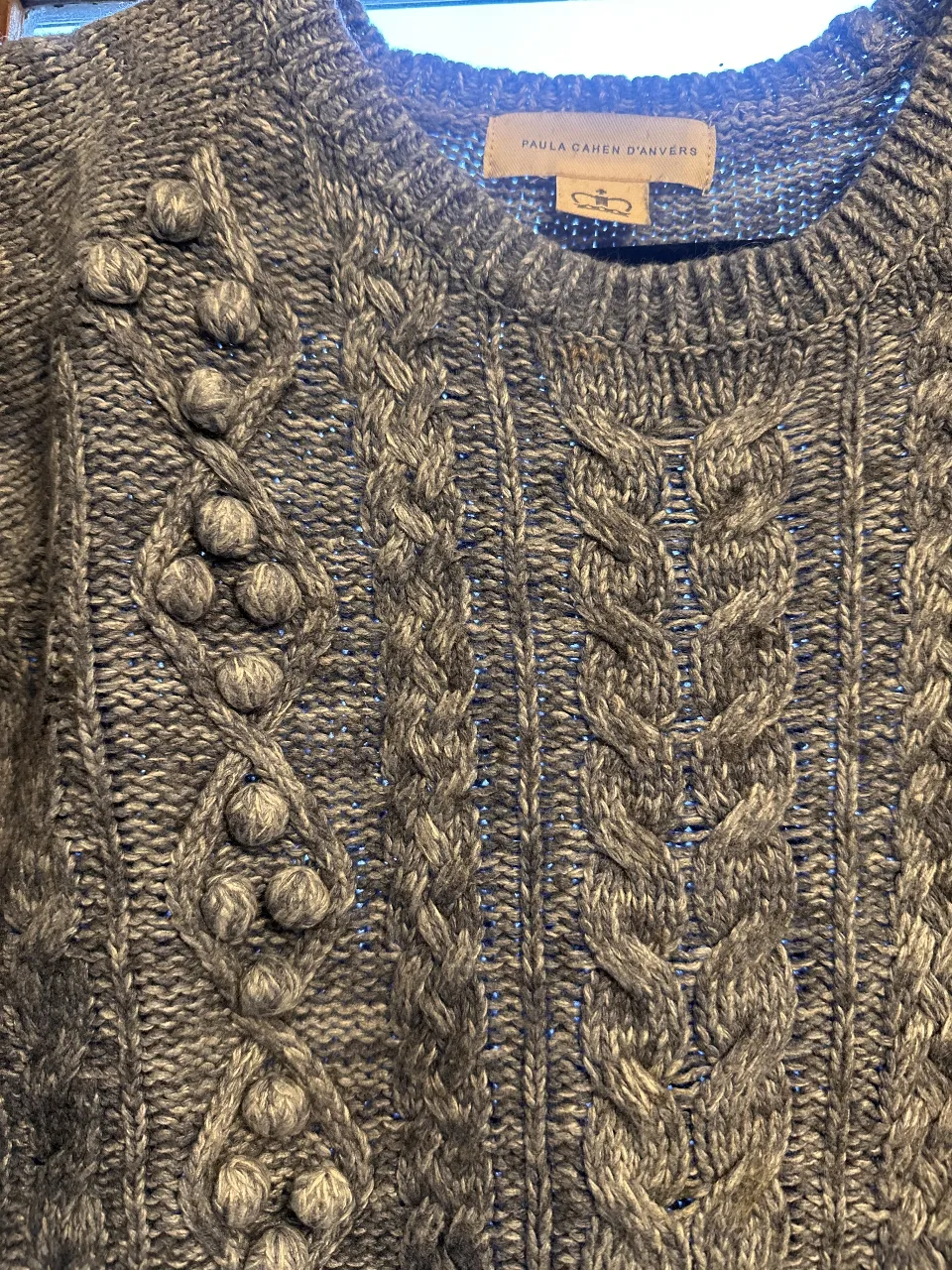 Sweater largo de punto grueso gris con detalles de diseño en relieve y pompones. Ideal para un look casual y abrigado.