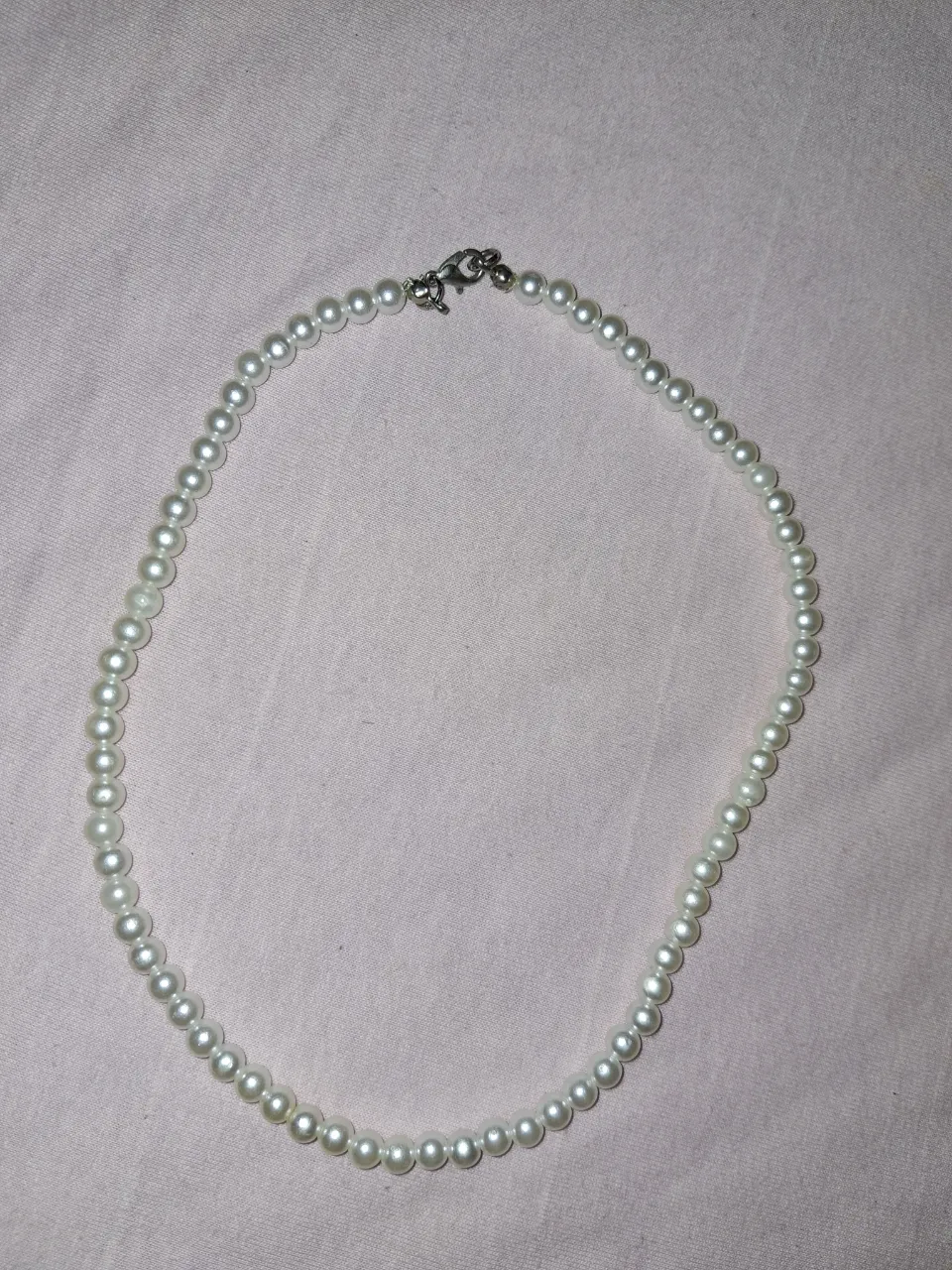 Collar de perlas blancas con cierre metálico.