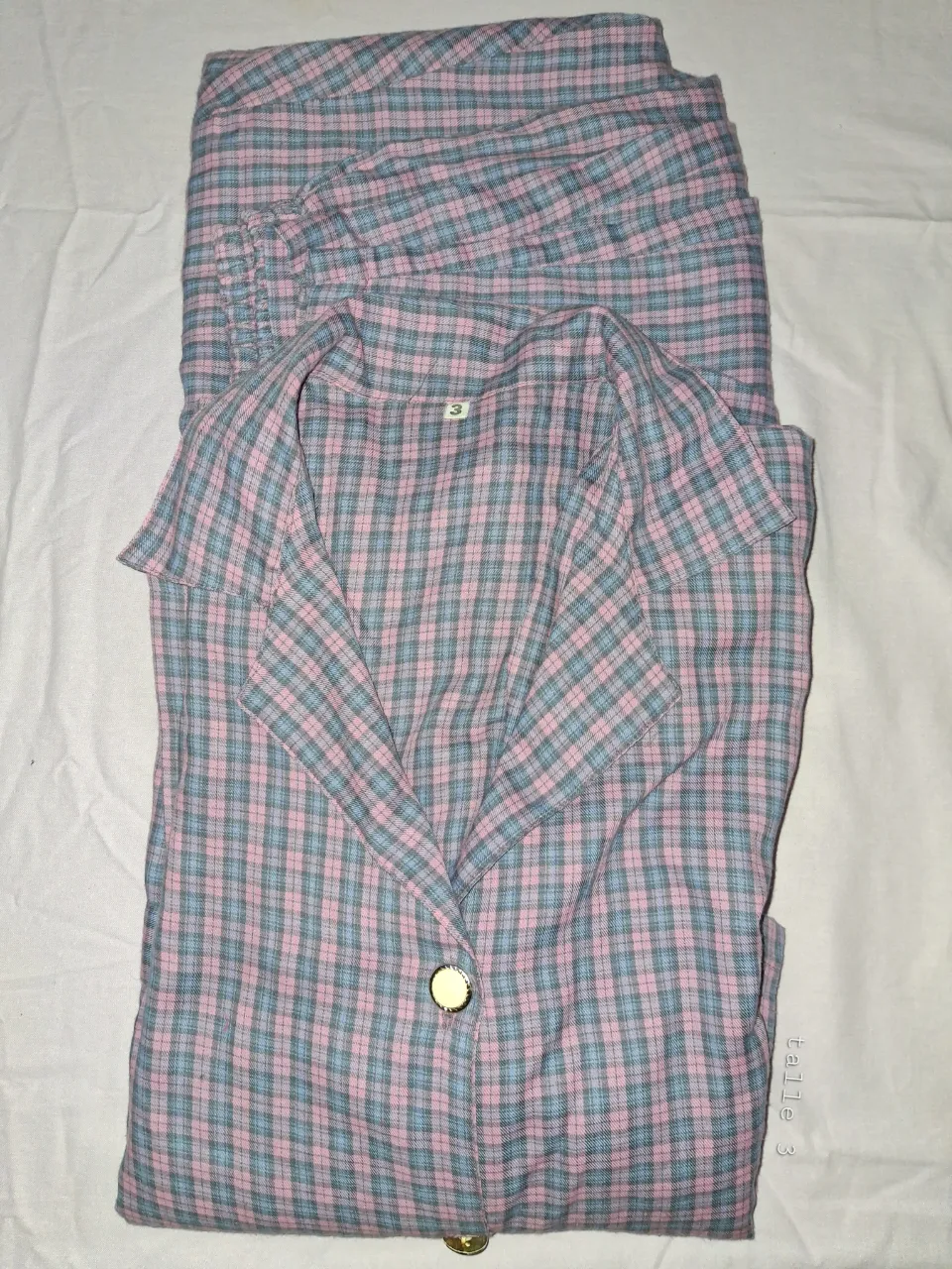 Conjunto de piyama, pantalón y camisa a cuadros en tonos rosa y celeste. 