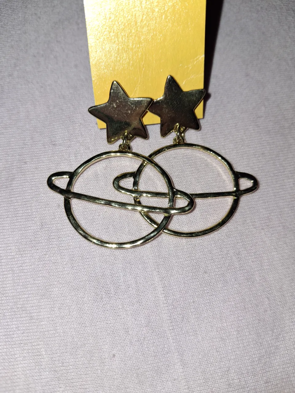 Aros colgantes dorados con forma de estrella y planeta con aro.