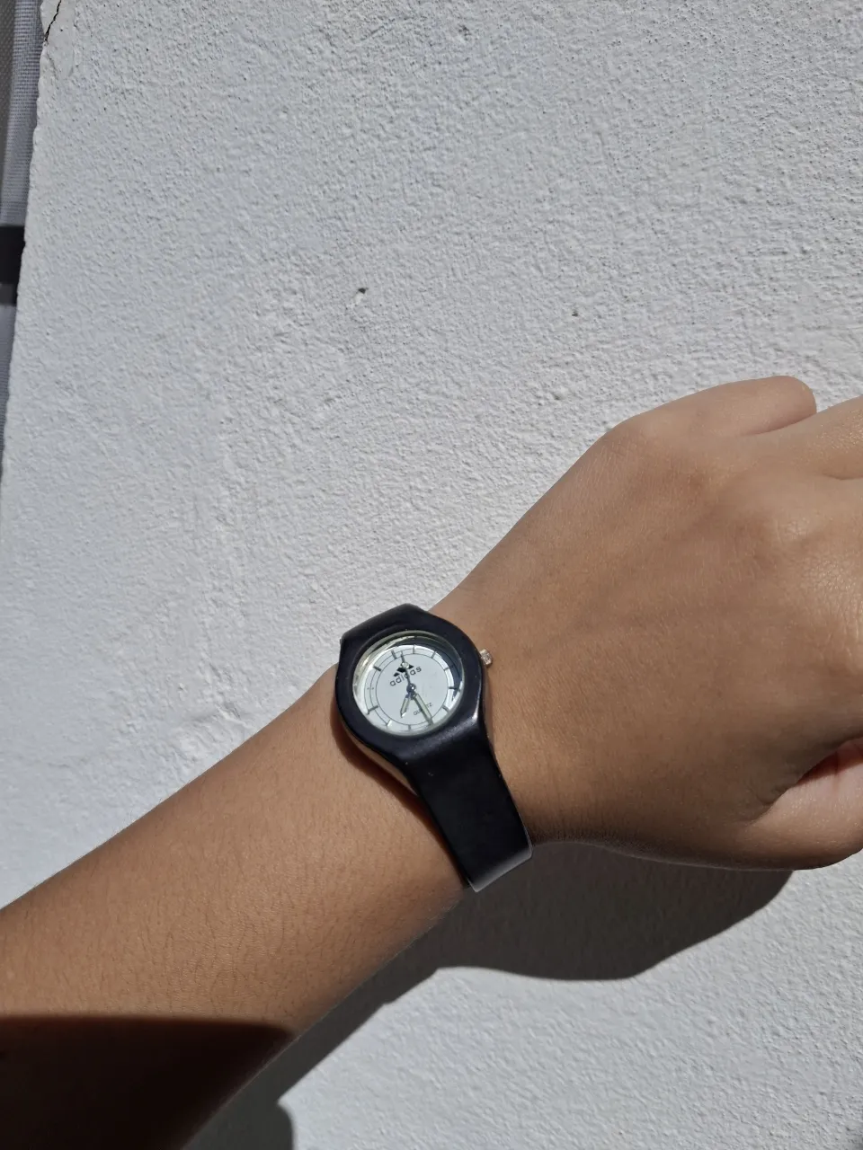 Reloj de pulsera negro con dial blanco y logo de Adidas.