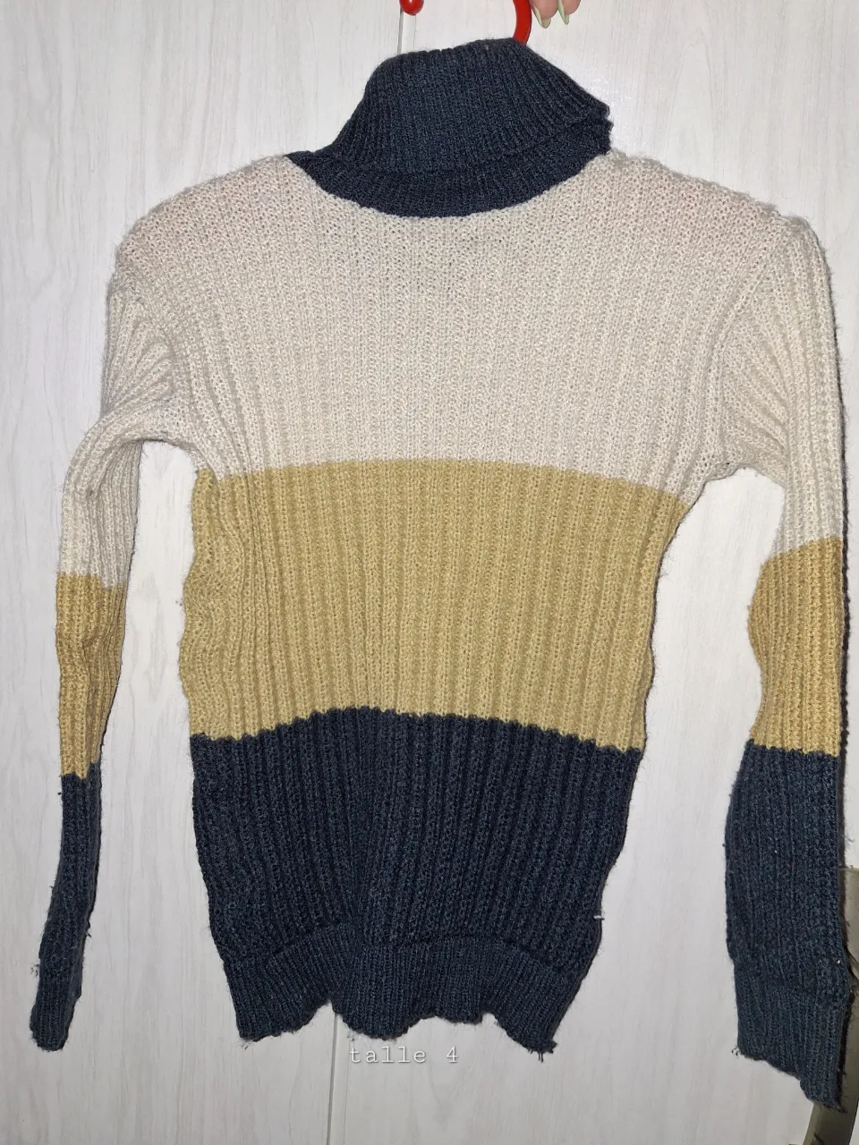 Sweater de lana tejido a rayas horizontales en color crudo, ocre y azul marino. Cuello alto.