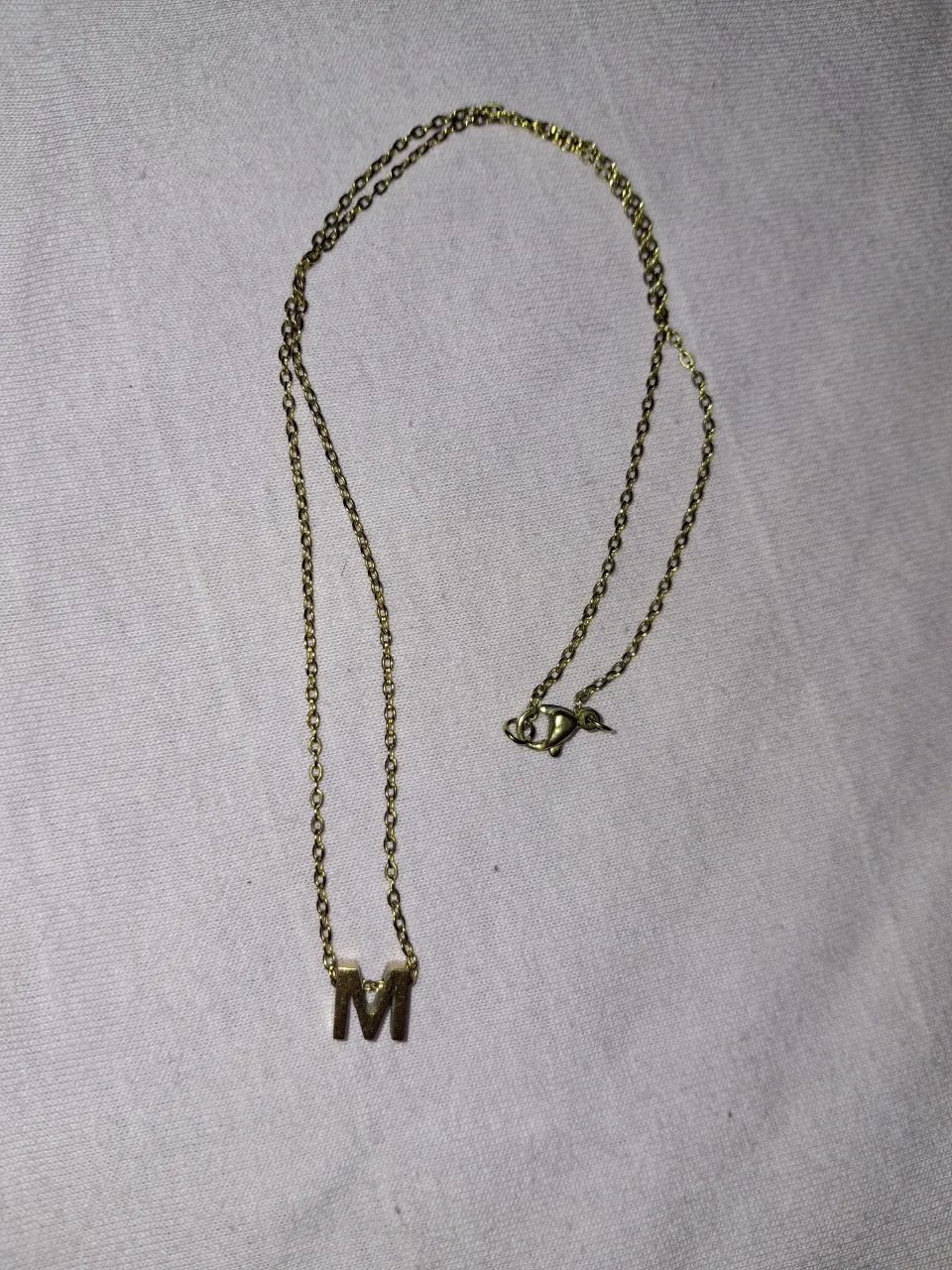 Cadena dorada con dije de letra M.