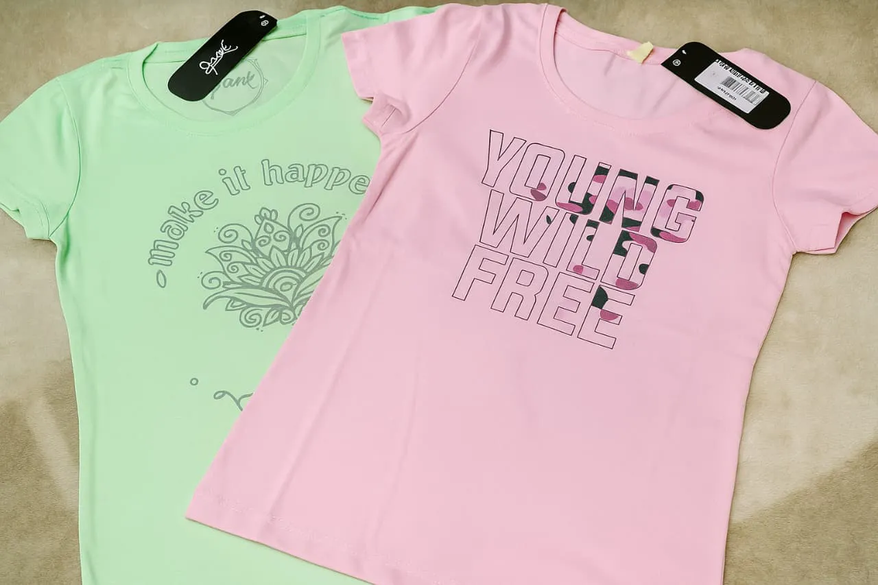 Remera manga corta color rosa con estampa "YOUNG WILD FREE" en negro y camuflado. Remera manga corta color verde menta con estampa de mandala y frase "make it happen" en gris.