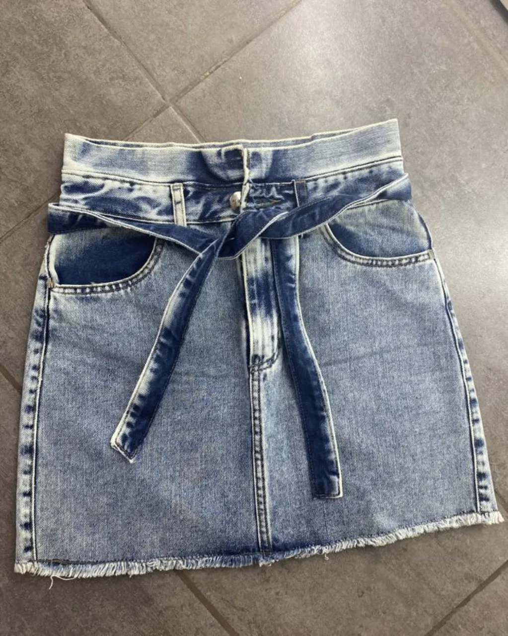 Pollera Melocoton de jean tiro alto con lazo para anudar en la cintura. Lavado desgastado con detalles en blanco. Dobladillo deshilachado.
poco uso, excelente estado