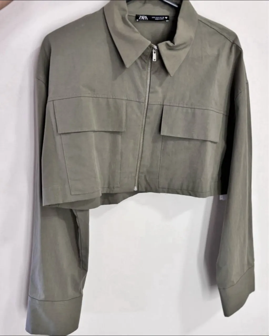 Camisa/campera corta de color verde militar con cuello y cierre metálico al frente. Posee dos bolsillos con solapa en la parte superior delantera y puños con botones.
nuevo sin uso! 