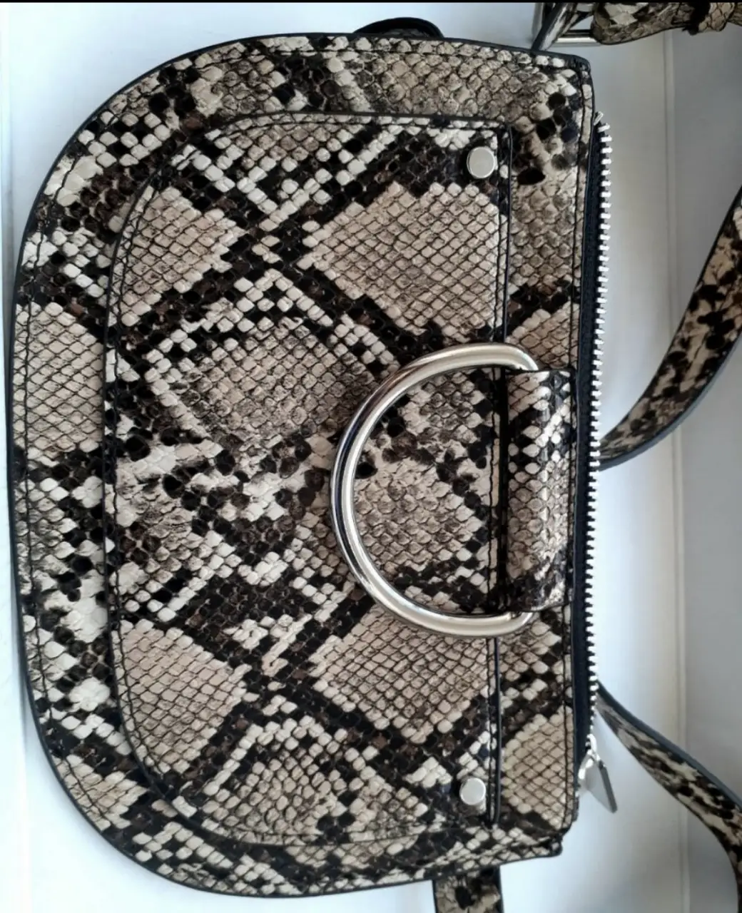 Cartera bandolera con estampado de serpiente. Diseño semicircular con detalle de aro metálico. Ideal para un look moderno y audaz. riñonera Zara chica ideal para salir de noche 