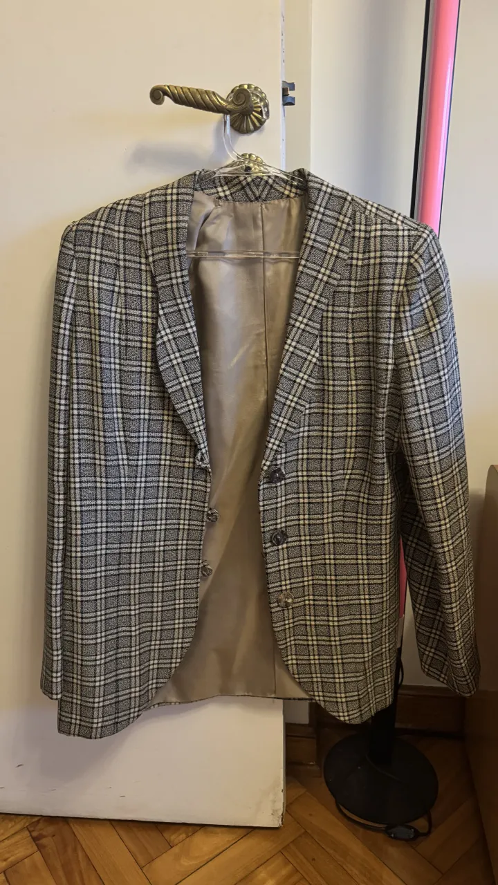 Blazer a cuadros de corte clásico, ideal para un look elegante y sofisticado. Perfecto para combinar con pantalones de vestir o jeans para un estilo más casual.
