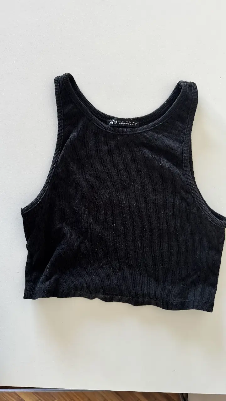 Musculosa negra de tejido acanalado, ideal para un look casual y moderno. Perfecta para combinar con jeans o shorts.
