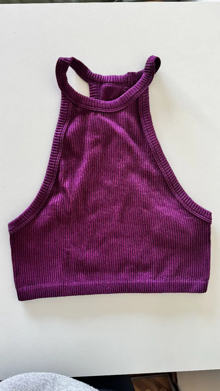 Top deportivo de mujer, color violeta, con diseño de cuello alto y espalda descubierta. Ideal para actividades de bajo impacto.