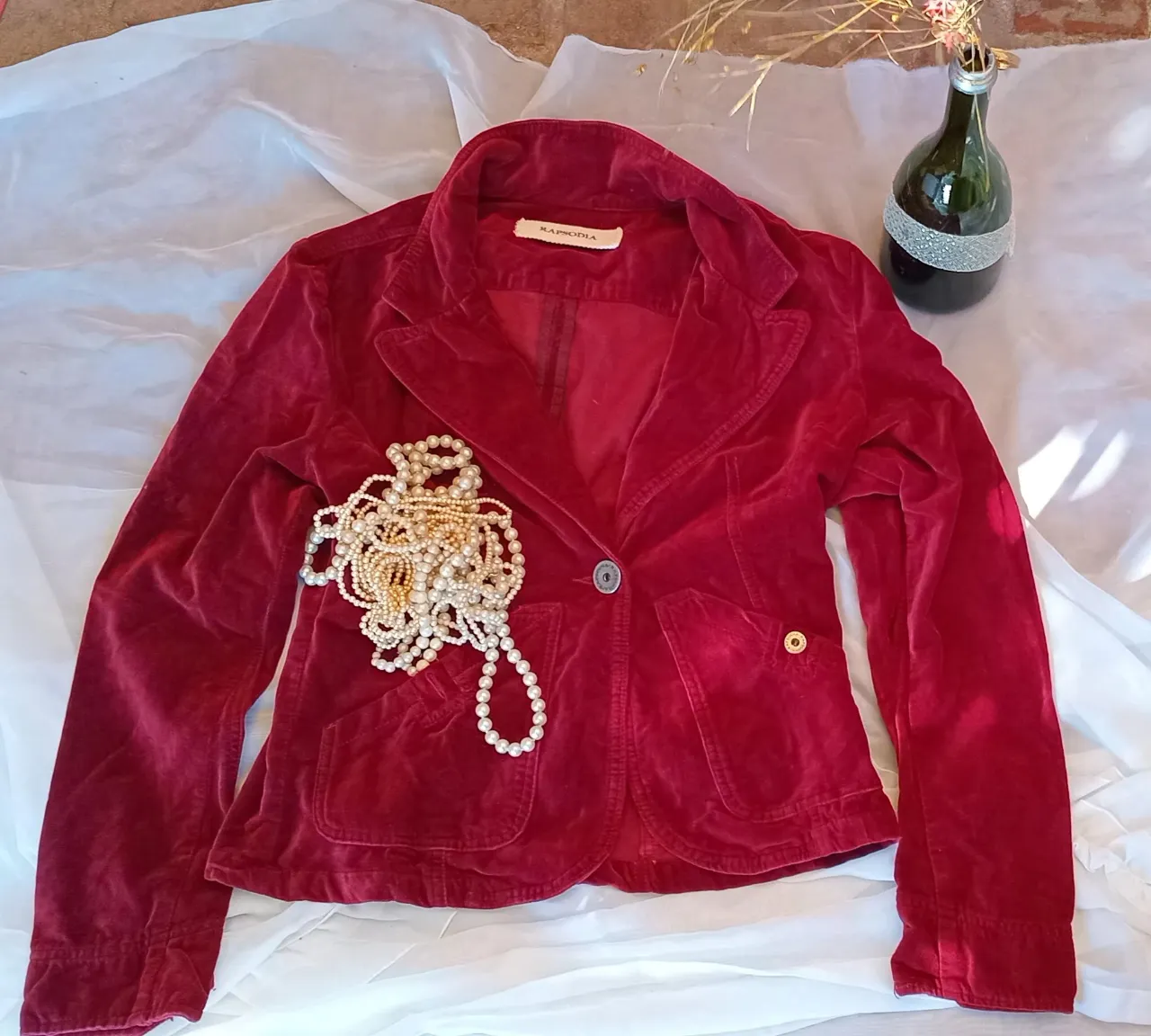 Blazer de terciopelo bordo, con un solo botón y bolsillos delanteros. Ideal para un look elegante y sofisticado.