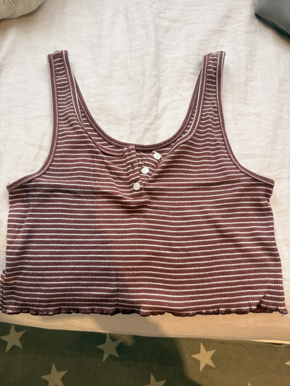 Musculosa a rayas marrones y blancas, con botones en el escote. Ideal para un look casual y cómodo.