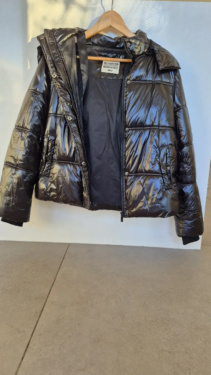 Campera inflable negra con capucha, ideal para el invierno. Posee cierre y bolsillos.