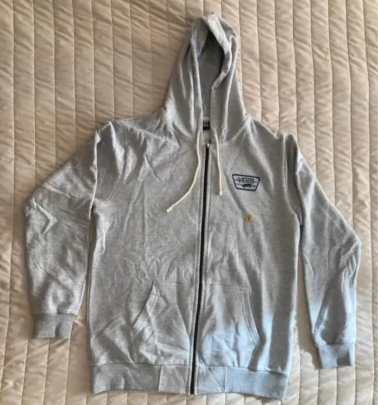 Buzo con cierre y capucha de hombre, marca Vans. Color gris con detalles en azul. Talle XL.