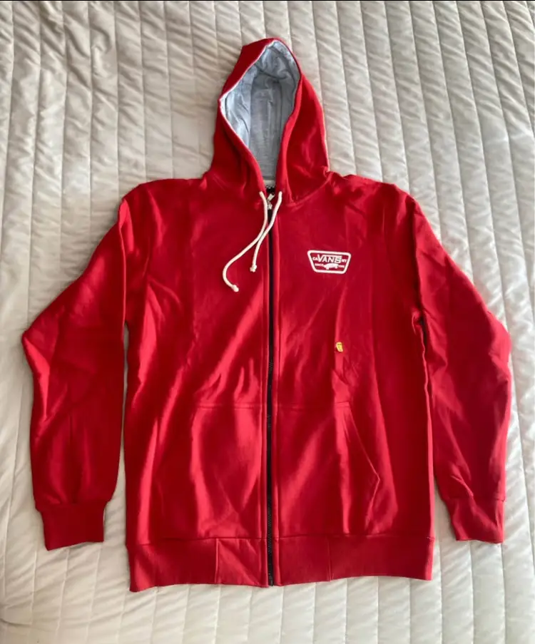 Buzo canguro con cierre y capucha, de color rojo con detalles en blanco. Posee el logo de Vans en el pecho y en la espalda. Ideal para un look casual y urbano.