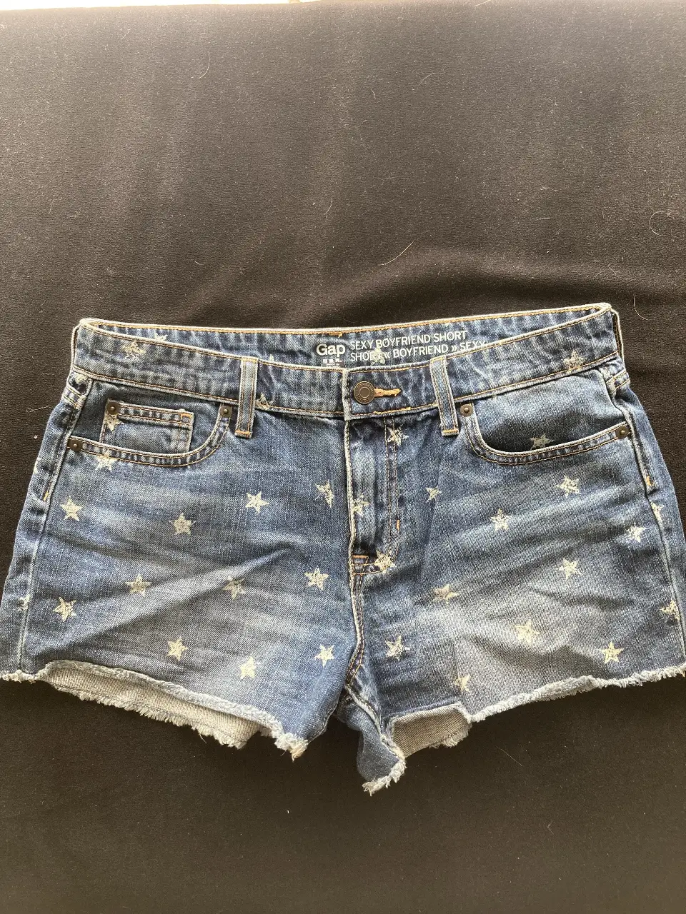 Short de jean de mujer, tiro medio, con estampado de estrellas blancas. Marca Gap, estilo boyfriend, ideal para un look casual y fresco.