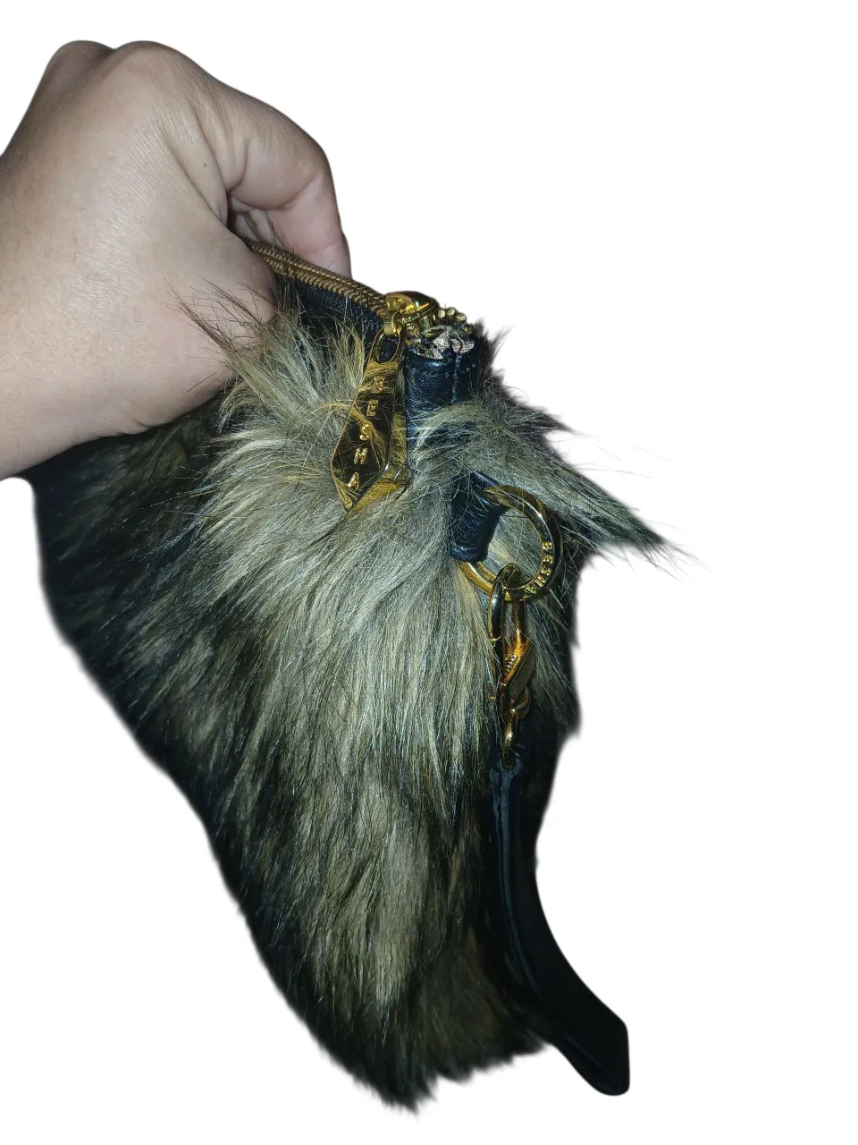 Cartera de mano con diseño de pelaje sintético en tonos marrones y negros. Detalles dorados en la cremallera y el asa. Ideal para un look de fiesta o salida.