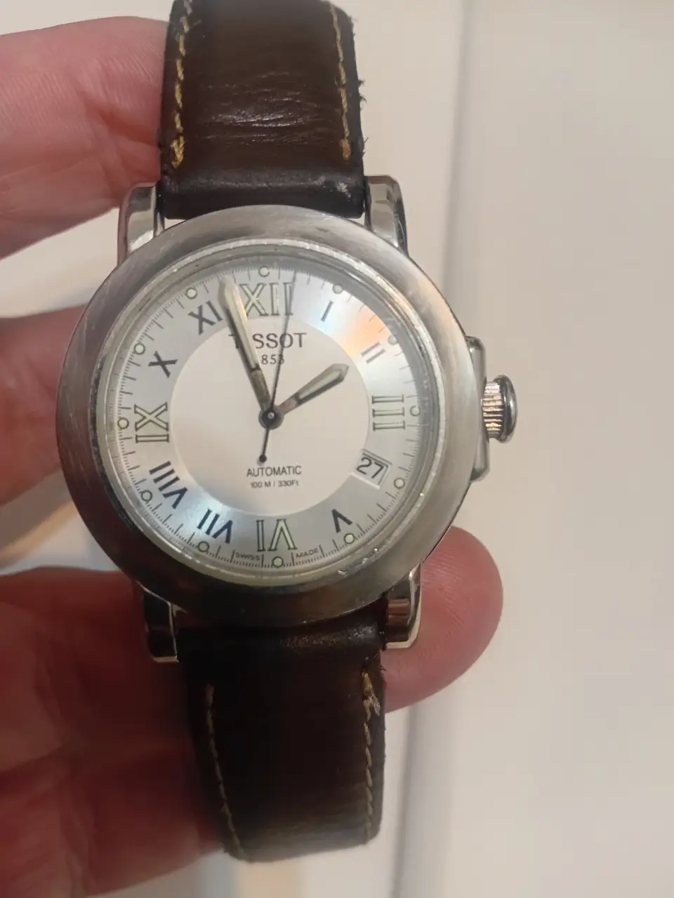 Reloj Tissot 853 automático con correa de cuero marrón. Diseño clásico con números romanos y fechador.