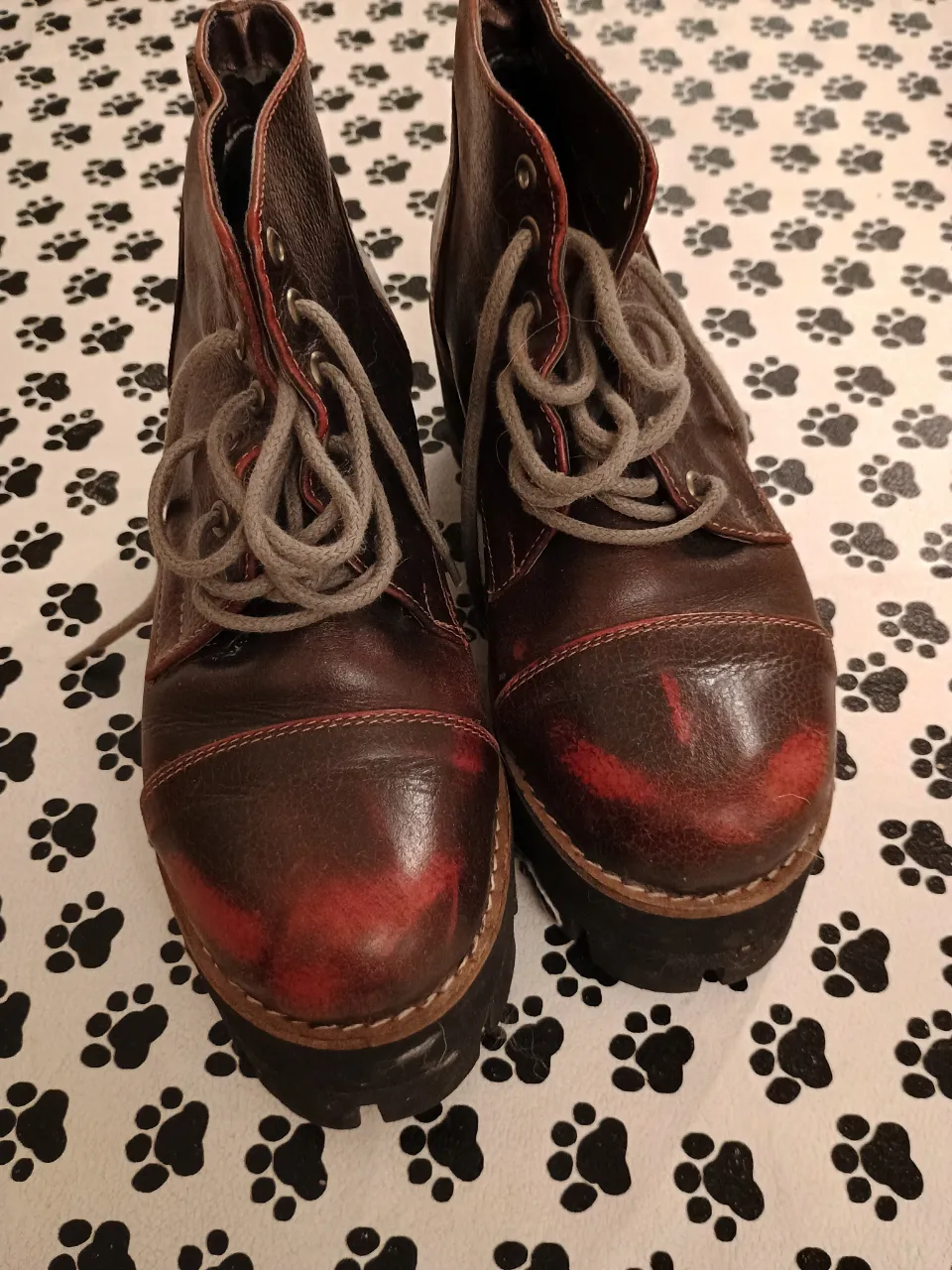 Botines de cuero marrón con detalles en rojo, cordones grises y suela gruesa. Estilo vintage, ideales para un look casual y urbano.