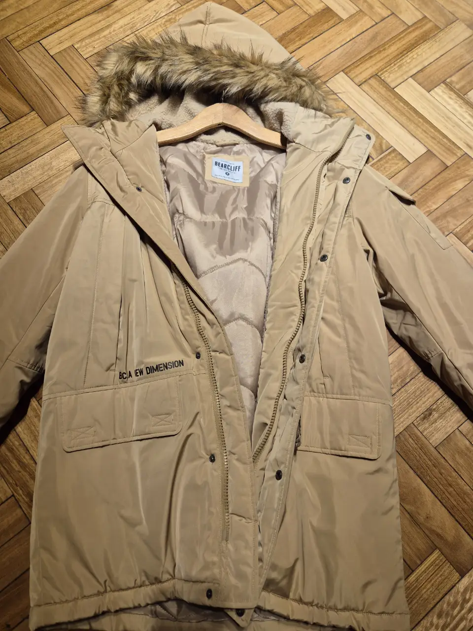 Campera de abrigo Bearcliff color khaki con capucha y detalles de piel sintética. Posee bolsillos frontales y cierre. Ideal para el invierno. Abrigada y de lluvia.