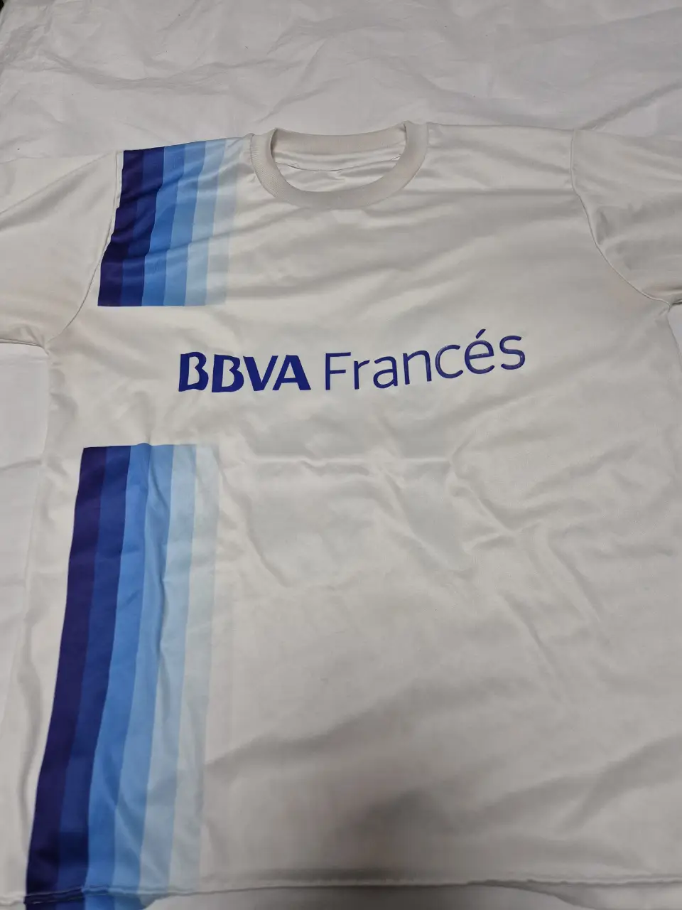 Remera de hombre BBVA Francés, color blanco con detalles en azul. Tiene el número 18 en la espalda. Ideal para fanáticos del fútbol.