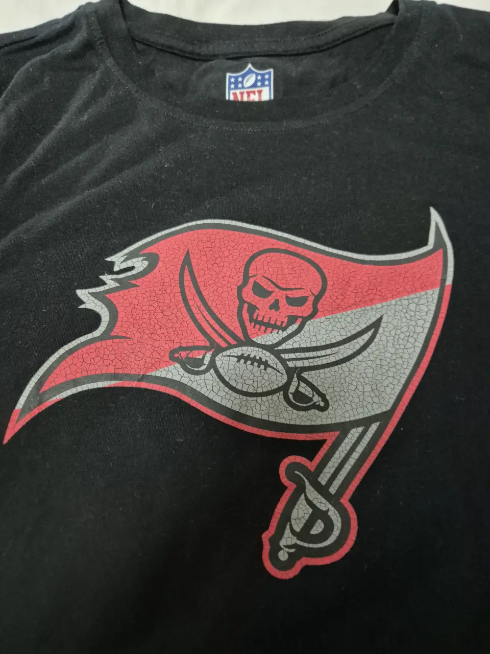 Remera negra de manga corta con el logo de los Tampa Bay Buccaneers estampado en el frente. Ideal para fanáticos del fútbol americano.
