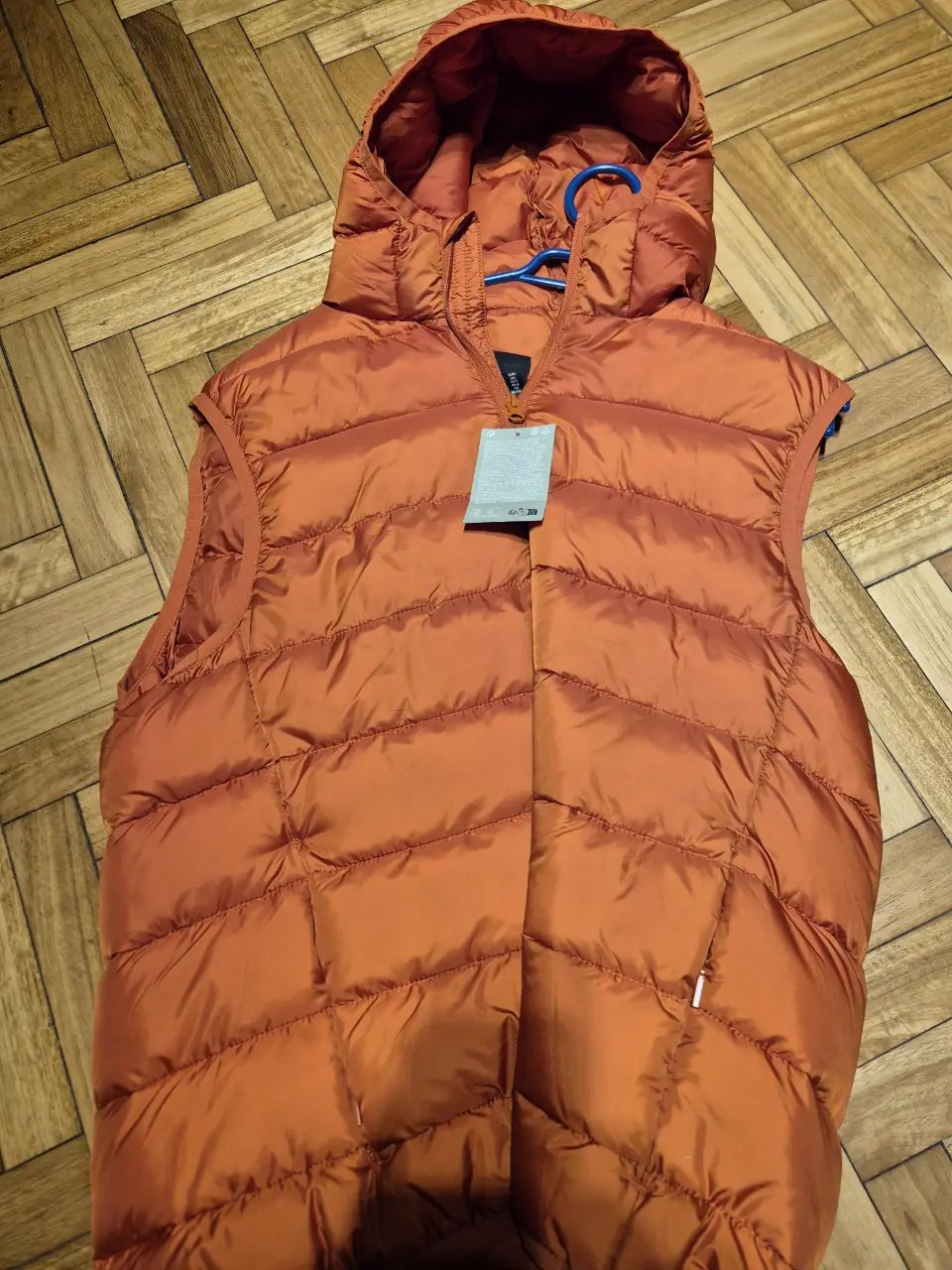 Chaleco naranja acolchado con capucha para hombre. Ideal para el invierno, este chaleco ofrece abrigo y estilo. Perfecto para un look casual y cómodo.
