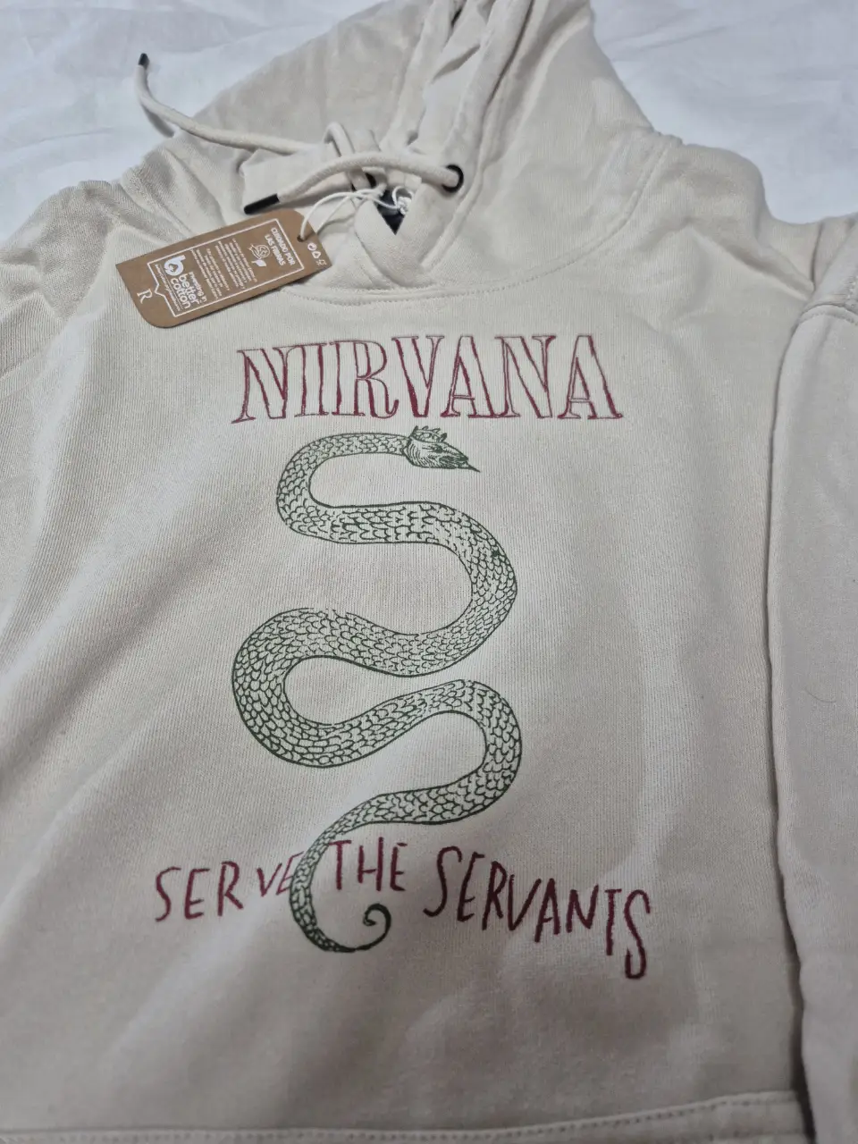 Buzo canguro de algodón color crudo con estampado de Nirvana y la frase "Serve the servants". Ideal para un look casual y cómodo. Importado. Es S oversize así que puede ser un M más normal.