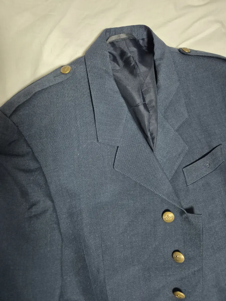 Chaqueta blazer azul marino con botones dorados tipo militar. Ideal para un look formal o semi-formal.