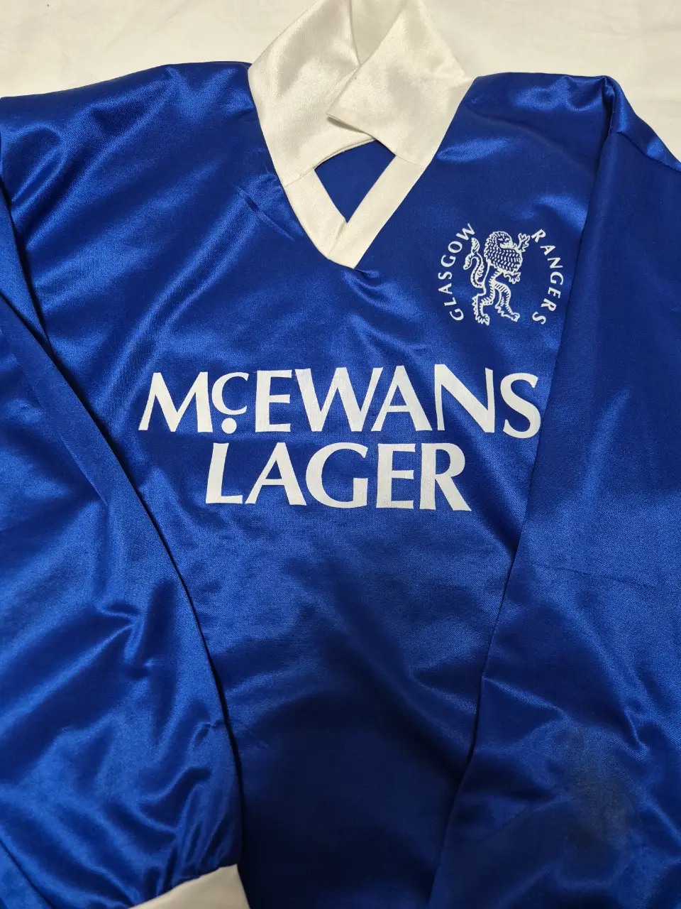 Camiseta de fútbol retro del Glasgow Rangers con el logo de McEwans Lager. Ideal para coleccionistas y fanáticos del fútbol.