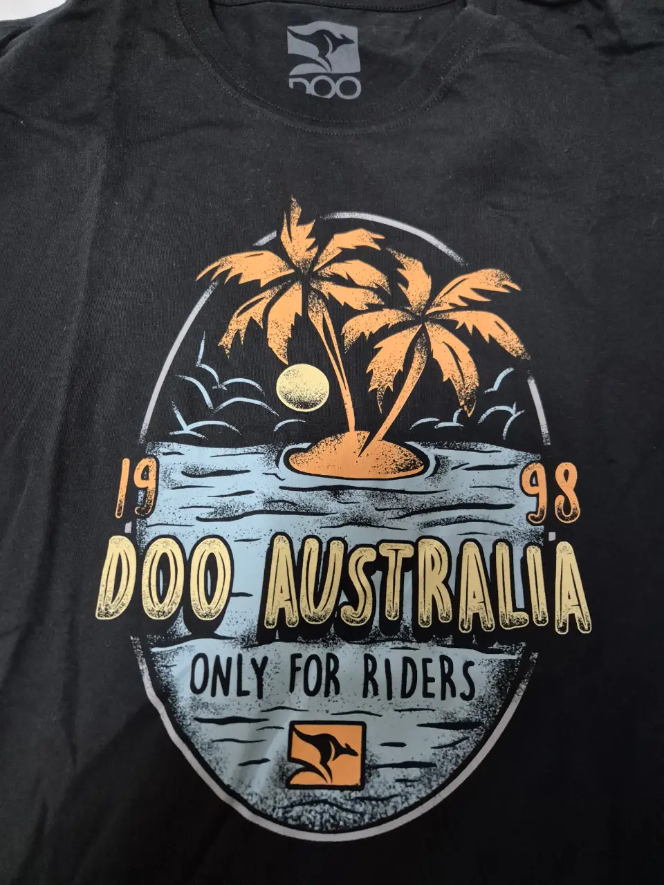Remera negra de Doo Australia, con estampado de palmeras y la inscripción 'Doo Australia Only for Riders'. Ideal para un look casual y relajado.