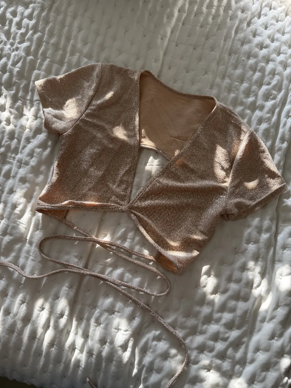Top corto de mujer, color dorado brillante, con diseño cruzado y tiras para atar. Ideal para fiestas y eventos especiales.