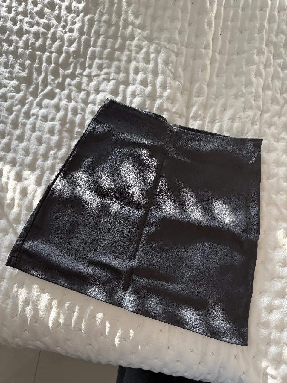 Minifalda de cuero sintético negra, ideal para un look moderno y versátil. Perfecta para salidas o eventos especiales.