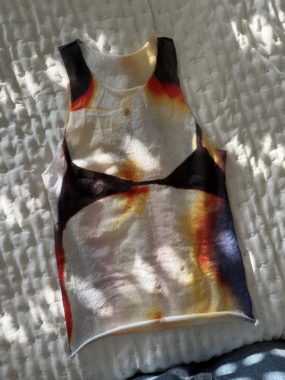 Top de red con estampado artístico. Ideal para un look moderno y audaz. Perfecto para combinar con jeans tiro bajo o una pollera.