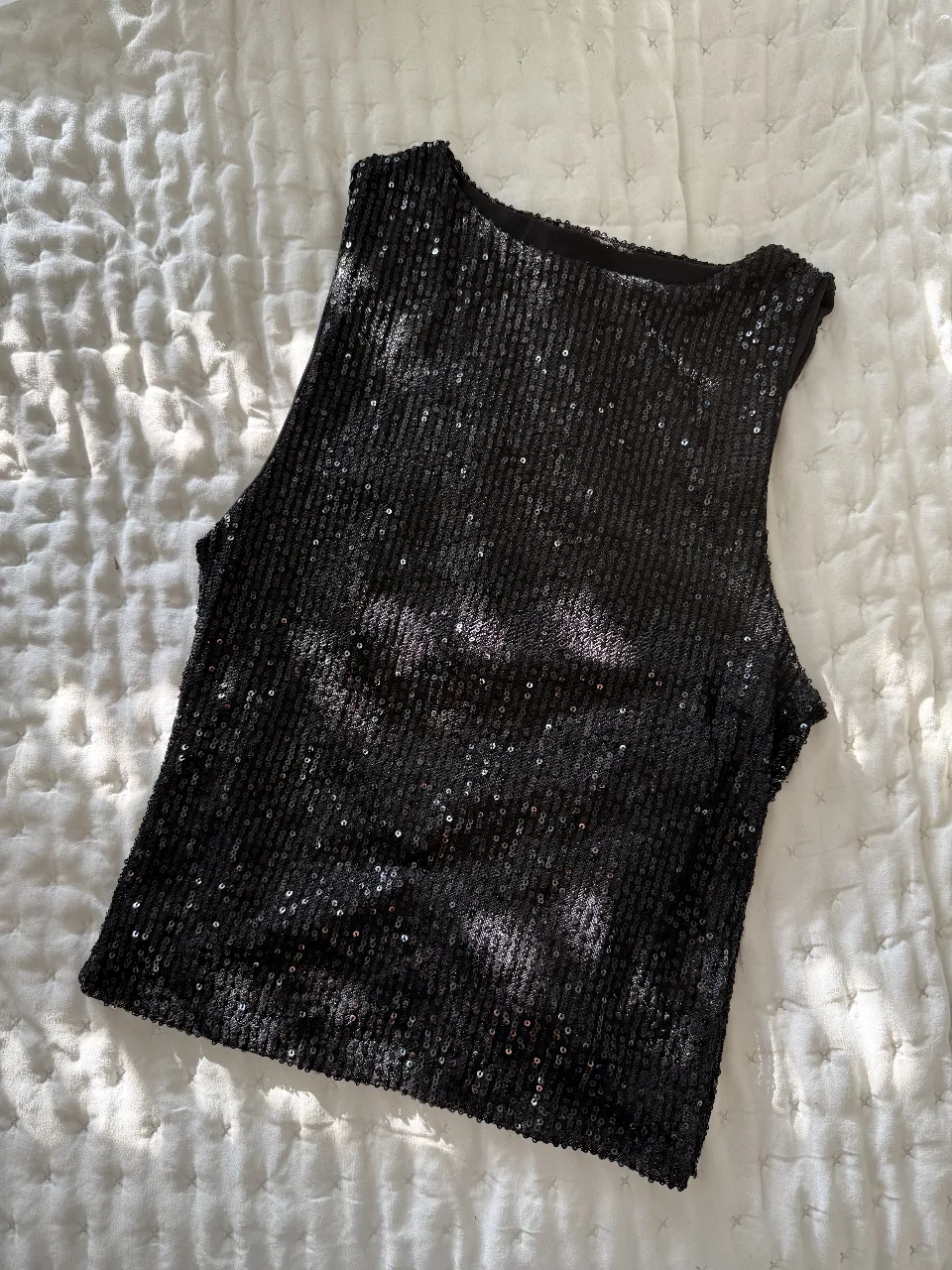 Top negro con lentejuelas, ideal para fiestas y salidas nocturnas. Un básico que no puede faltar en tu guardarropa.