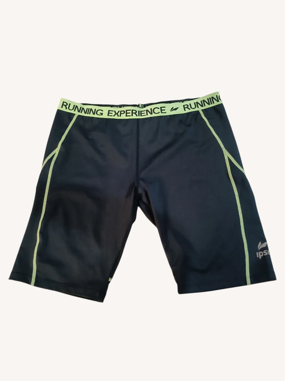 Short running deportivo negro con costuras laterales y cintura en color verde lima. La cintura tiene la inscripción "RUNNING EXPERIENCE". Posee un bolsillo trasero con cierre.
📏Cintura 40cm. Muslo 48 cm.