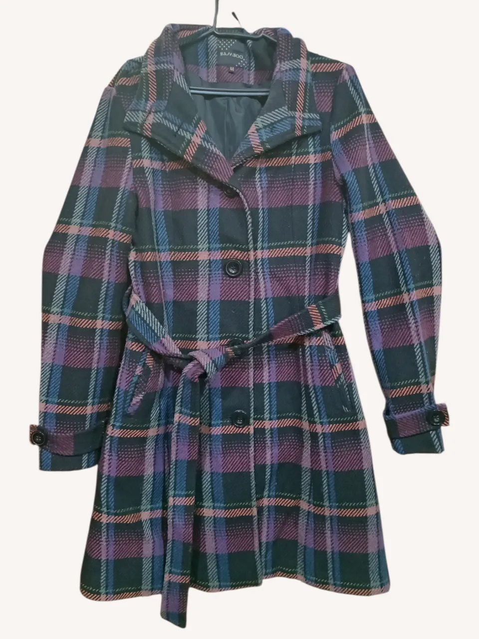 Tapado a cuadros escoceses en tonos negro, fucsia, azul y naranja. Posee cuello solapa, cierre de botones al frente, cinturón de tela para atar y puños con botón.
Tiene dos botones de repuesto.
‼️Detalle: manchita en la manga (última foto).